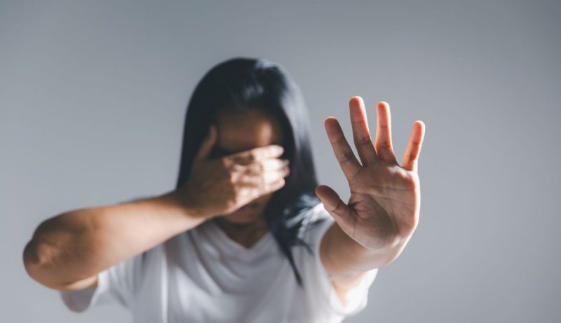 Una mujer tapa su cara con una mano y estira la otra en señal de freno | Foto de 123fr/thainoipho