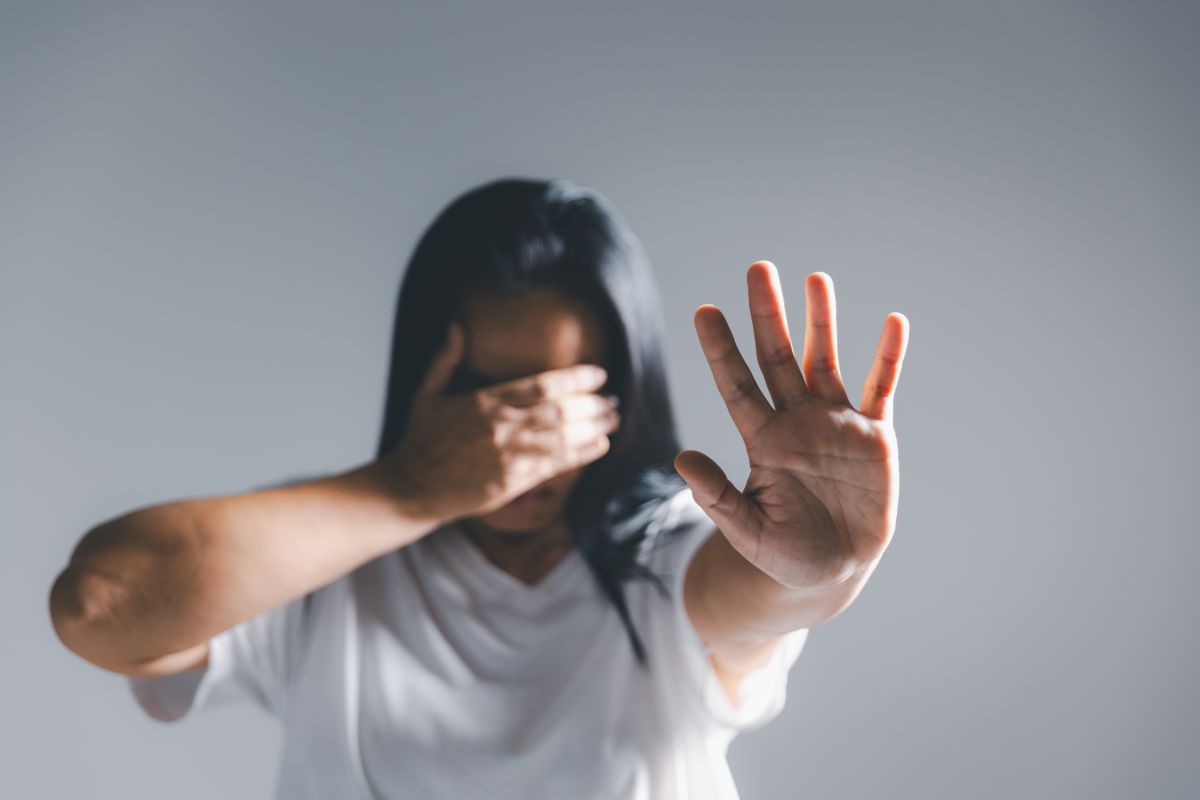 Una mujer tapa su cara con una mano y estira la otra en señal de freno | Foto de 123fr/thainoipho
